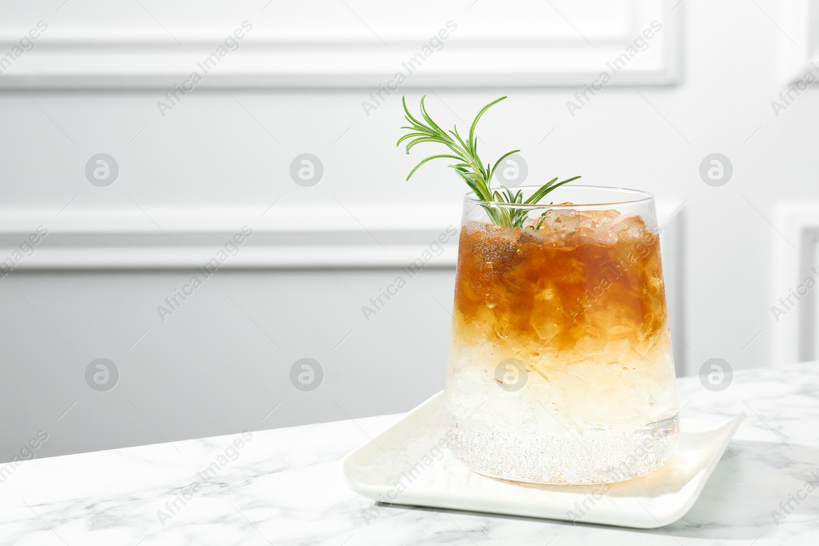 Photo of Refreshing espresso tonic drink with rosemary on white marble table, space for text