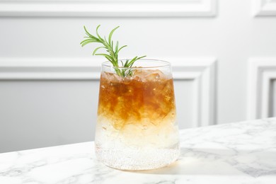 Photo of Refreshing espresso tonic drink with rosemary on white marble table