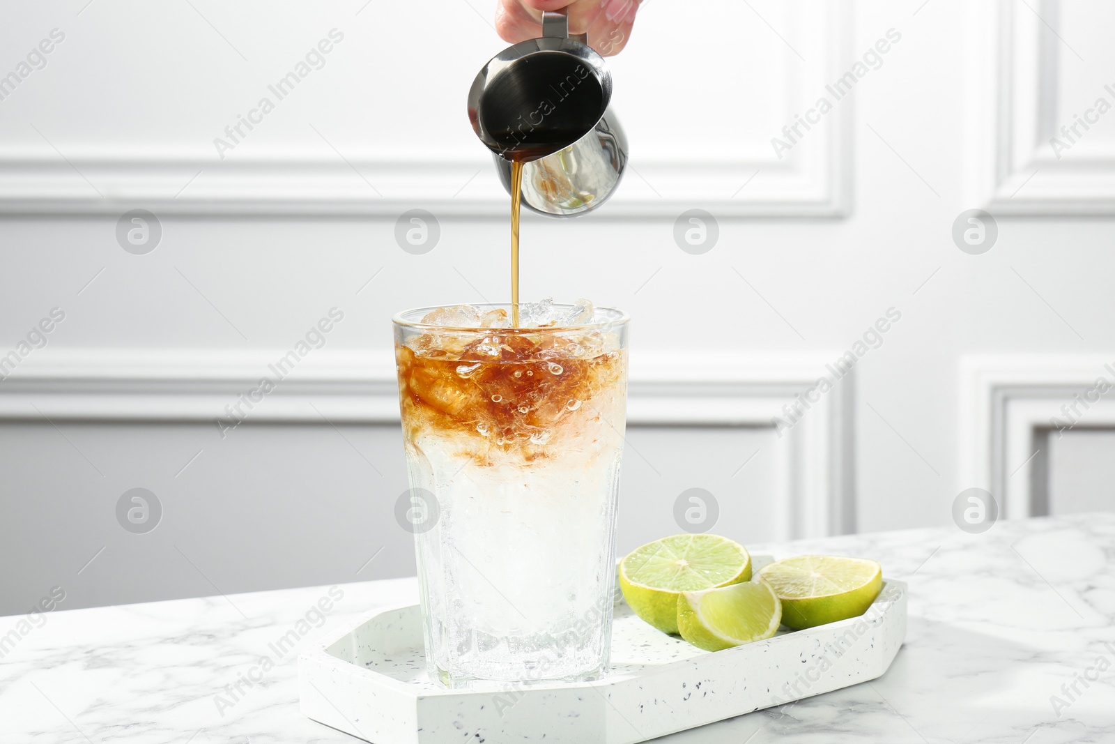 Photo of Woman making refreshing espresso tonic drink at white marble table, closeup