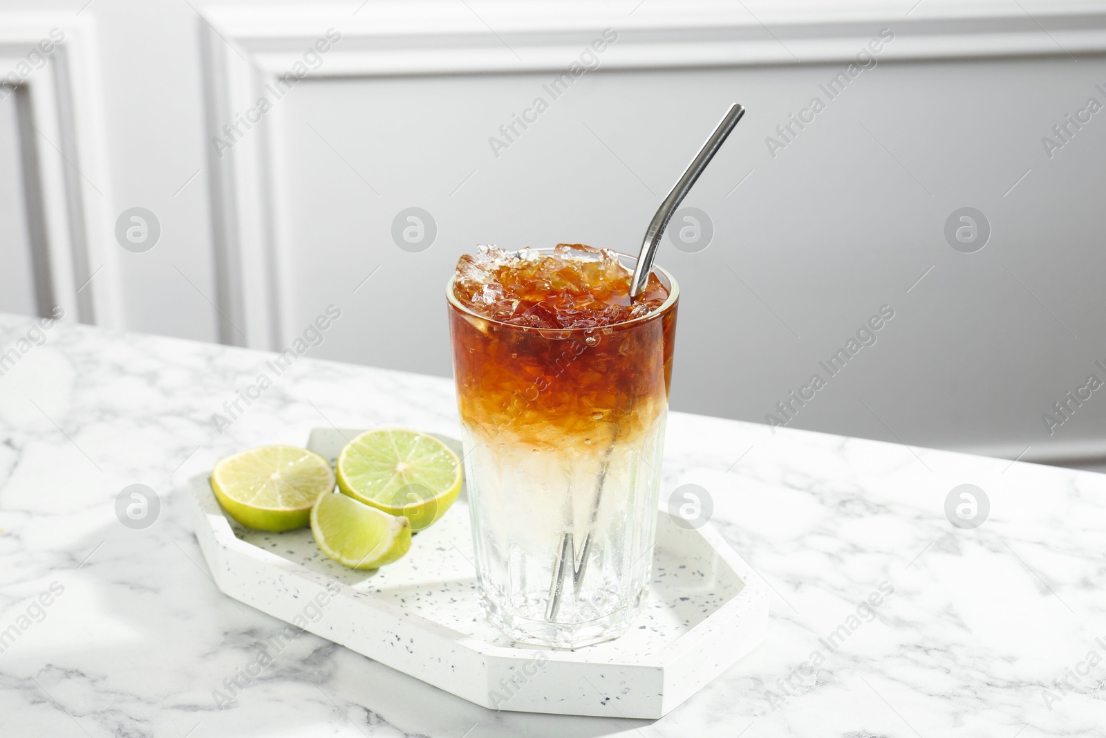 Photo of Refreshing espresso tonic drink and lime on white marble table