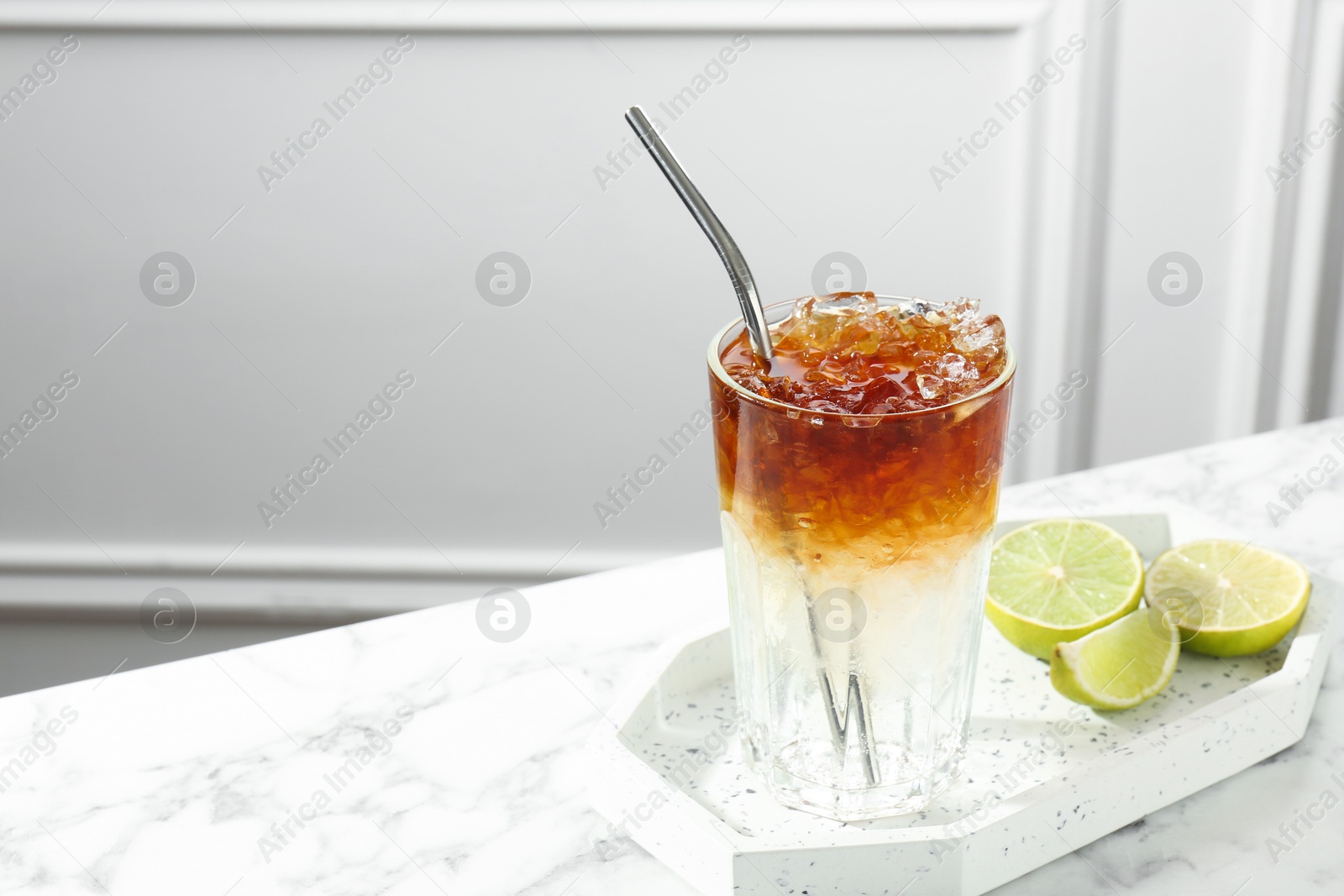 Photo of Refreshing espresso tonic drink and lime on white marble table, space for text