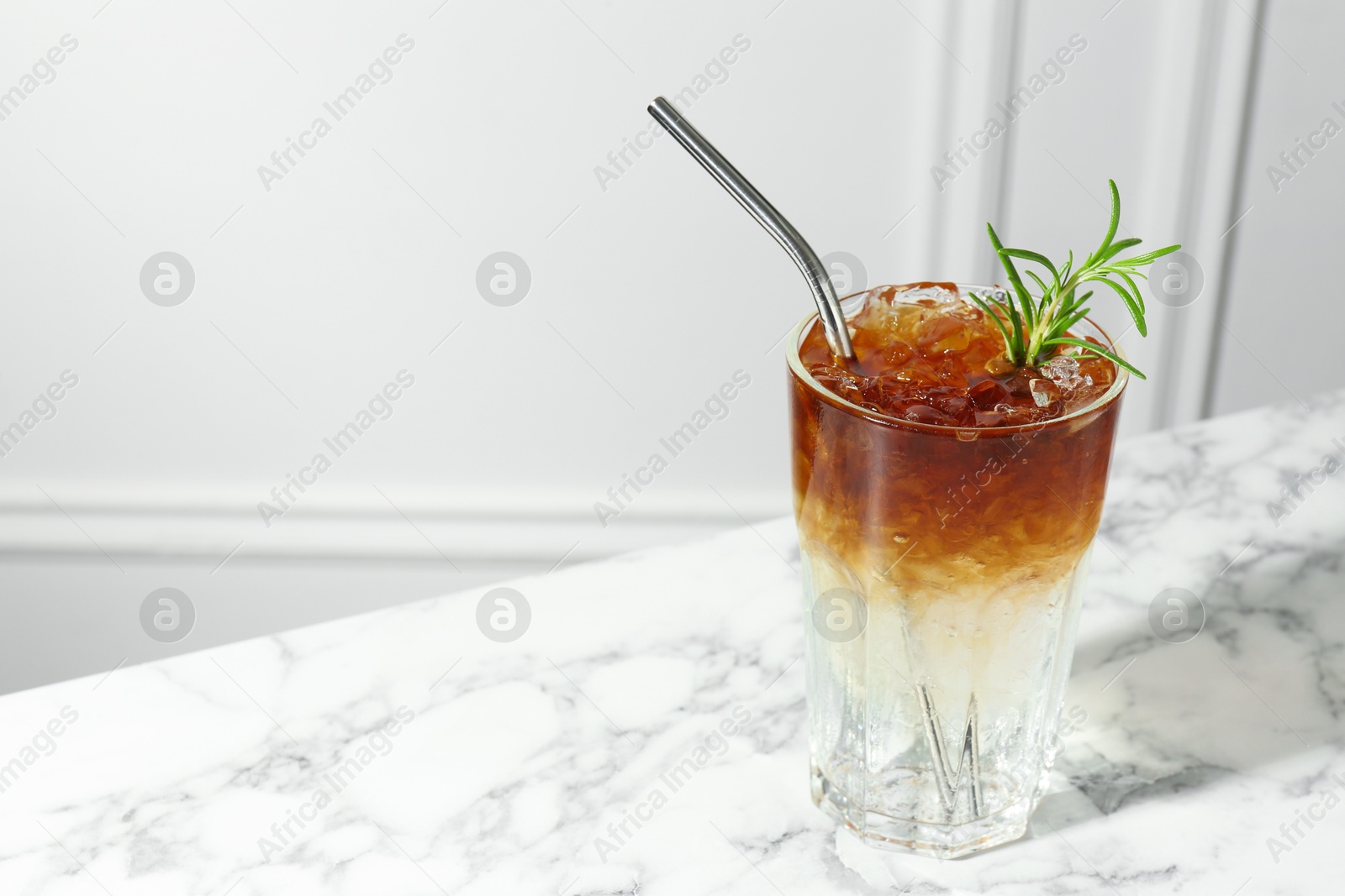 Photo of Refreshing espresso tonic drink with rosemary on white marble table, space for text