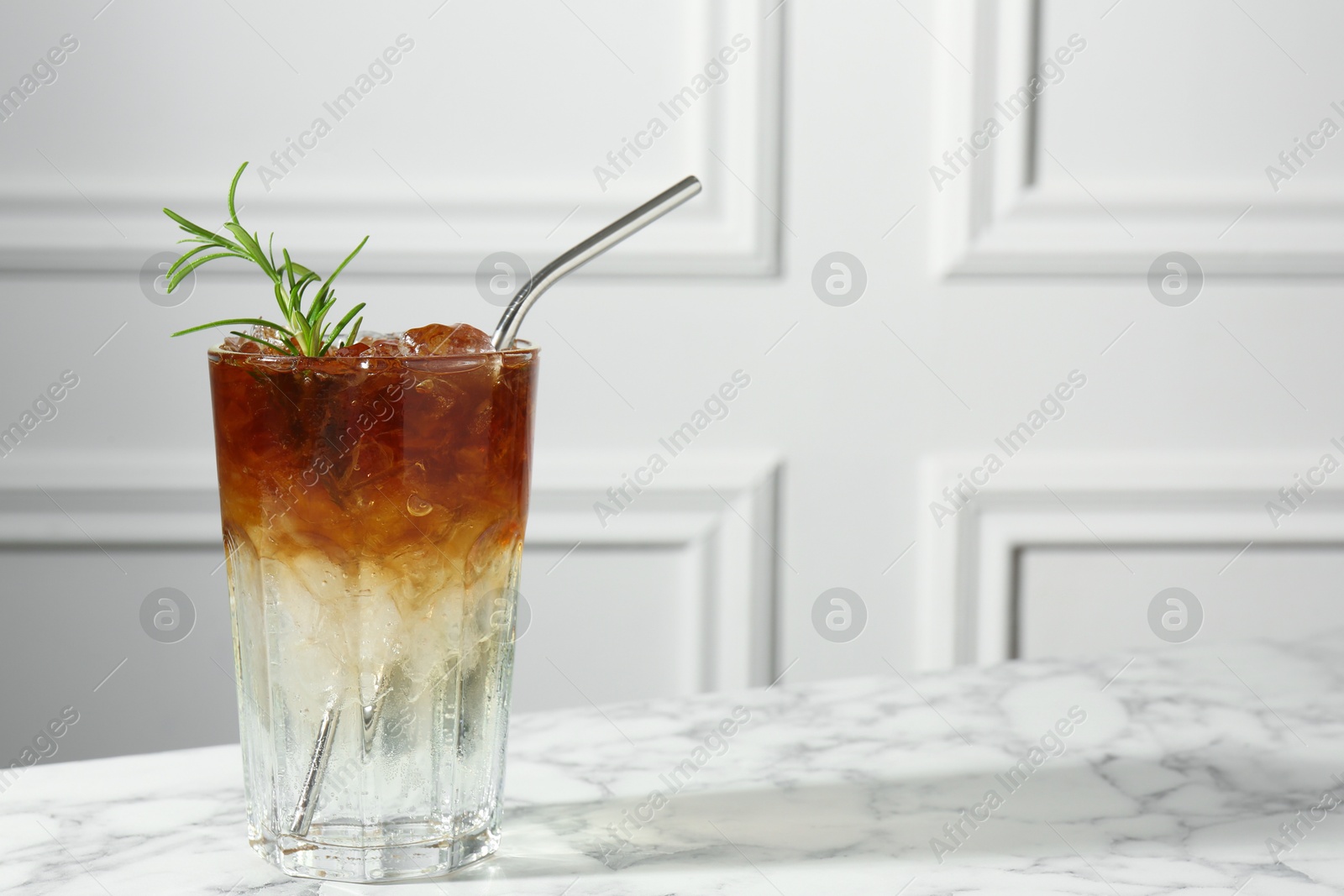 Photo of Refreshing espresso tonic drink with rosemary on white marble table, space for text