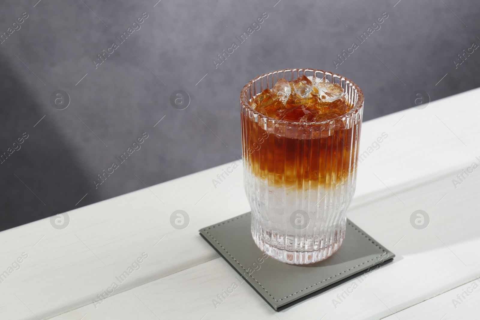 Photo of Refreshing espresso tonic drink on white wooden table, space for text