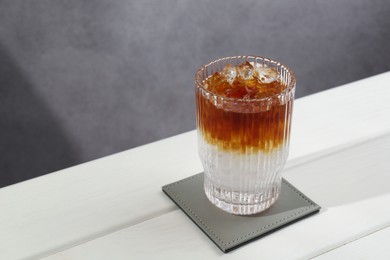 Photo of Refreshing espresso tonic drink on white wooden table, space for text