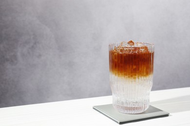 Refreshing espresso tonic drink on white wooden table, space for text