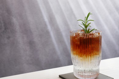 Photo of Refreshing espresso tonic drink with rosemary on white wooden table, space for text