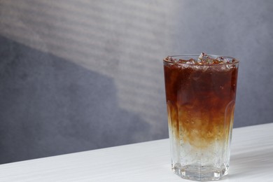 Refreshing espresso tonic drink on white wooden table, space for text