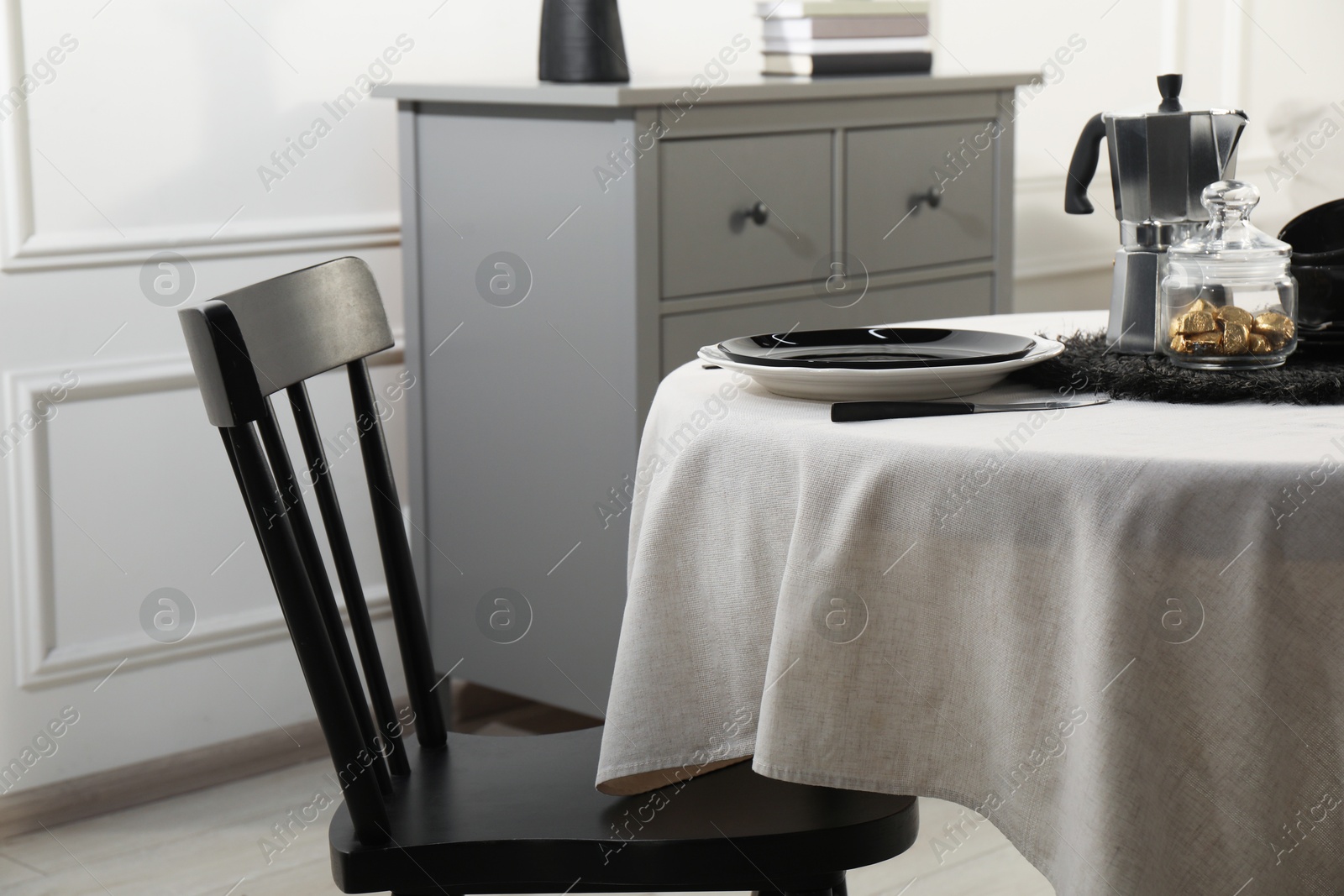 Photo of Stylish table setting with beautiful dishware and black chair in dining room