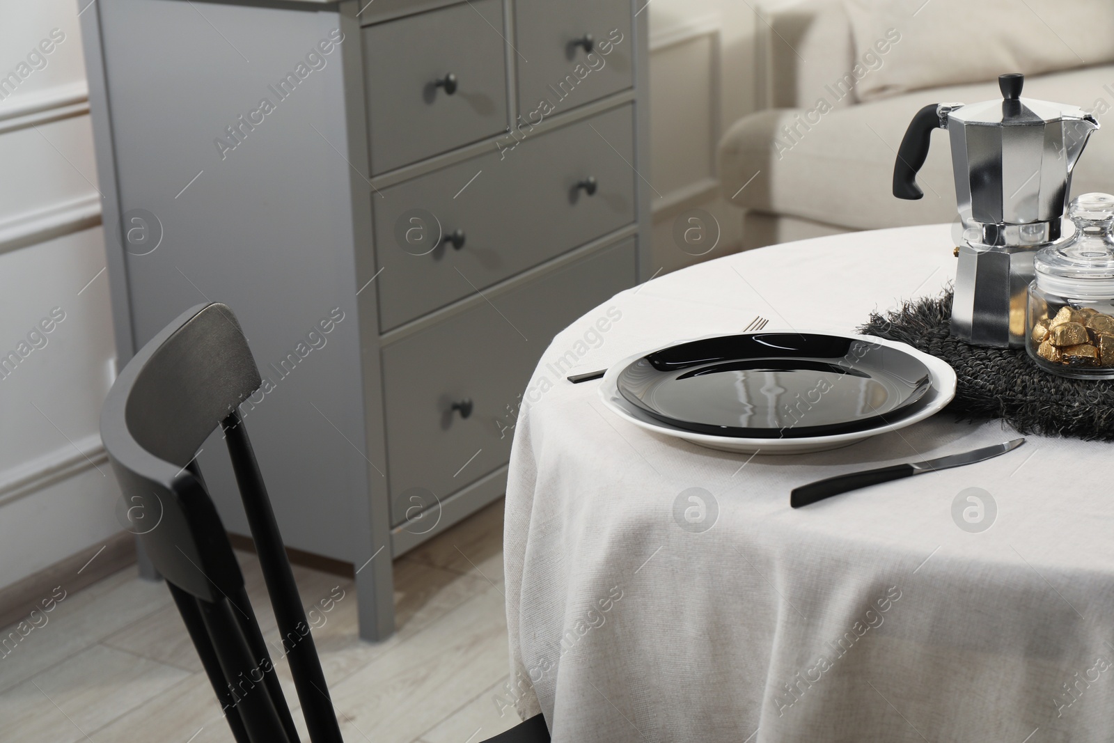 Photo of Stylish table setting with beautiful dishware and black chair in dining room