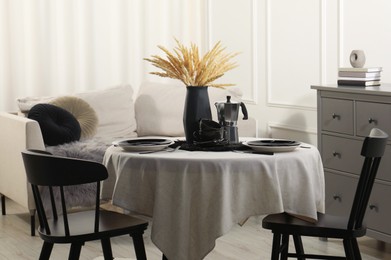 Photo of Stylish table setting with beautiful dishware and black chairs in dining room