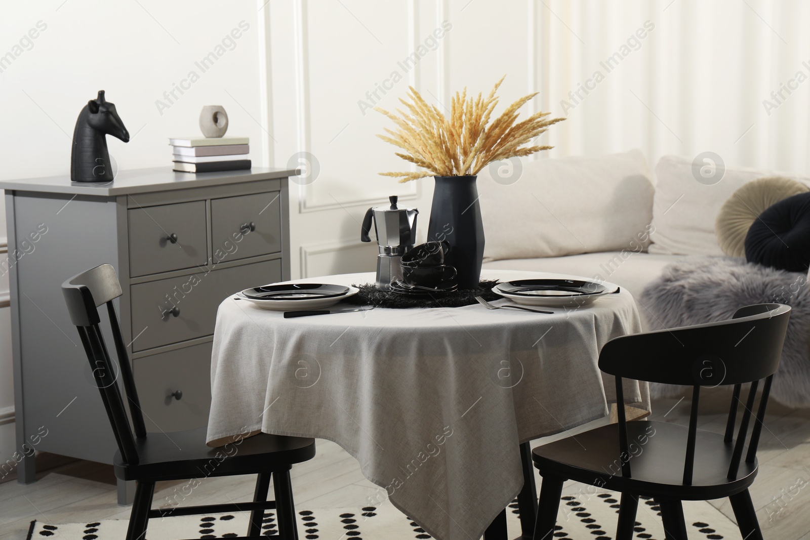 Photo of Stylish table setting with beautiful dishware and black chairs in dining room