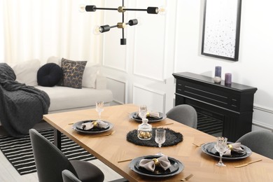 Photo of Stylish table setting with black dishware in dining room