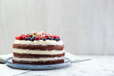 Photo of Delicious chocolate sponge cake with berries on white marble table. Space for text