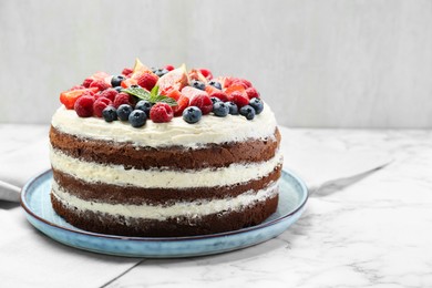 Photo of Delicious chocolate sponge cake with berries on white marble table