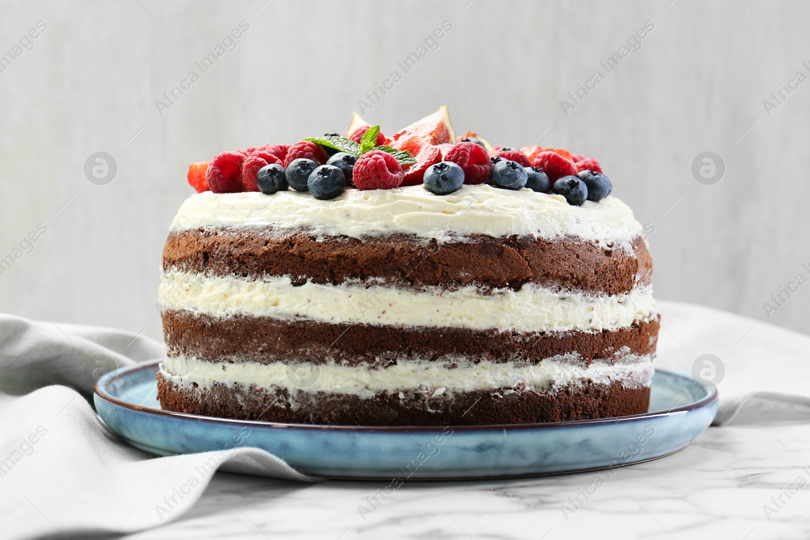 Photo of Delicious chocolate sponge cake with berries on white marble table