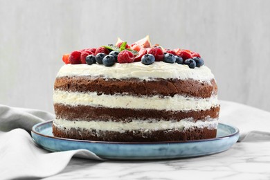 Photo of Delicious chocolate sponge cake with berries on white marble table