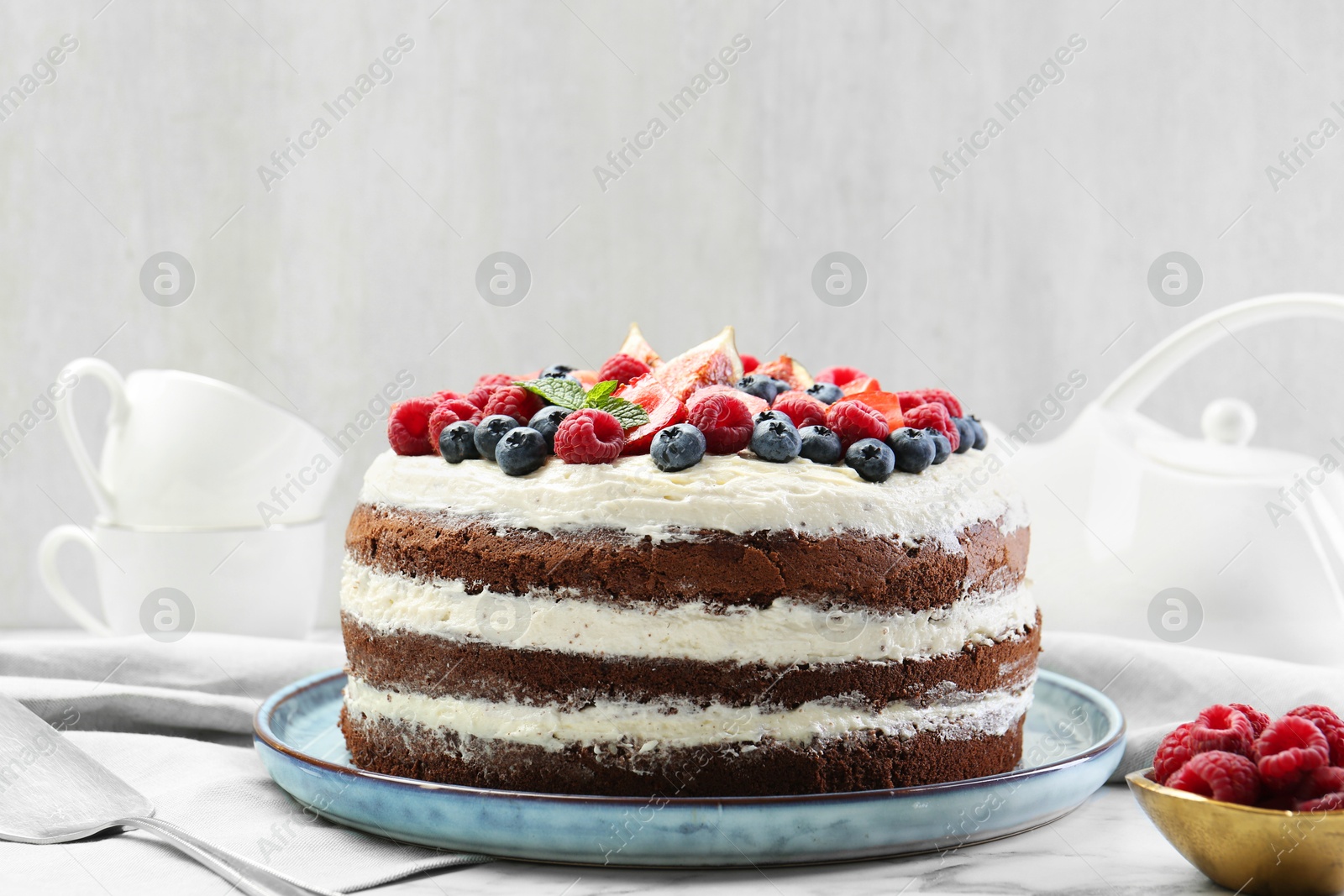 Photo of Delicious chocolate sponge cake with berries served on white table