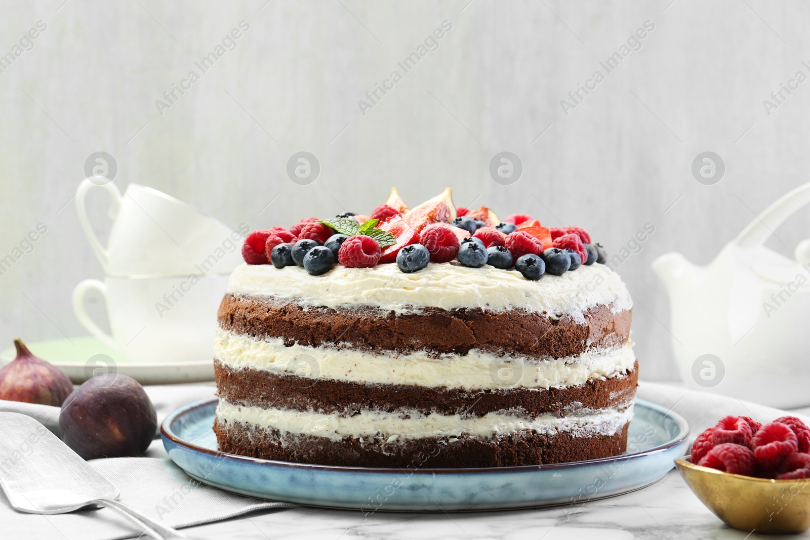 Photo of Delicious chocolate sponge cake with berries served on white table