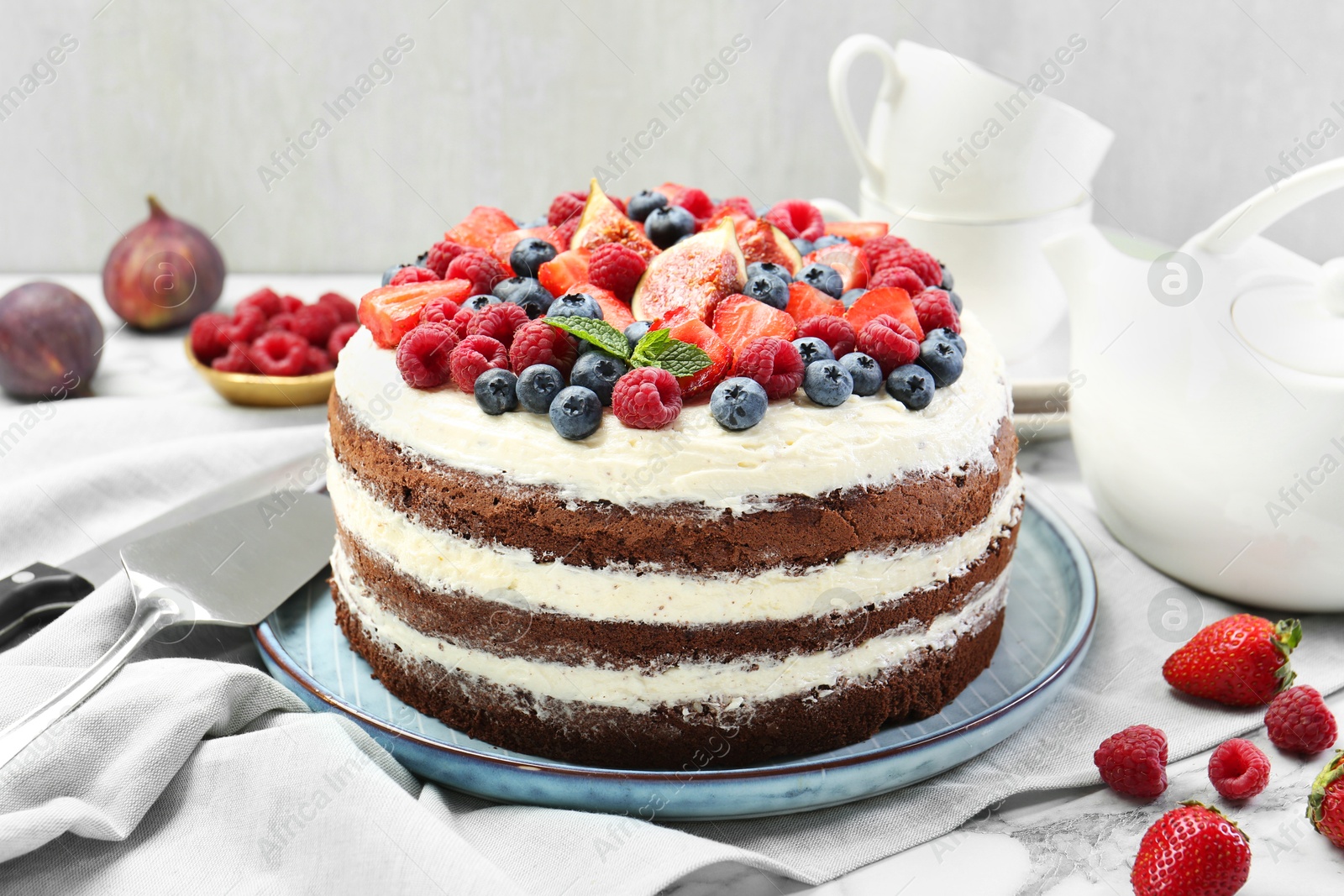 Photo of Delicious chocolate sponge cake with berries served on white table