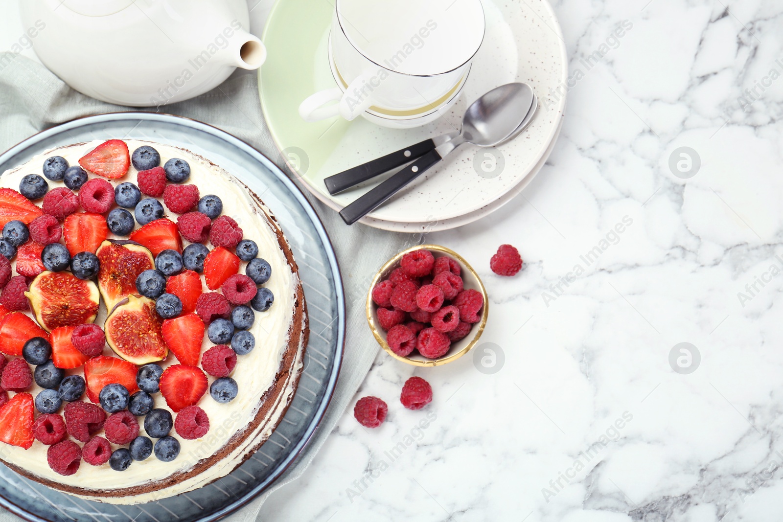 Photo of Delicious chocolate sponge cake with berries served on white marble table, flat lay