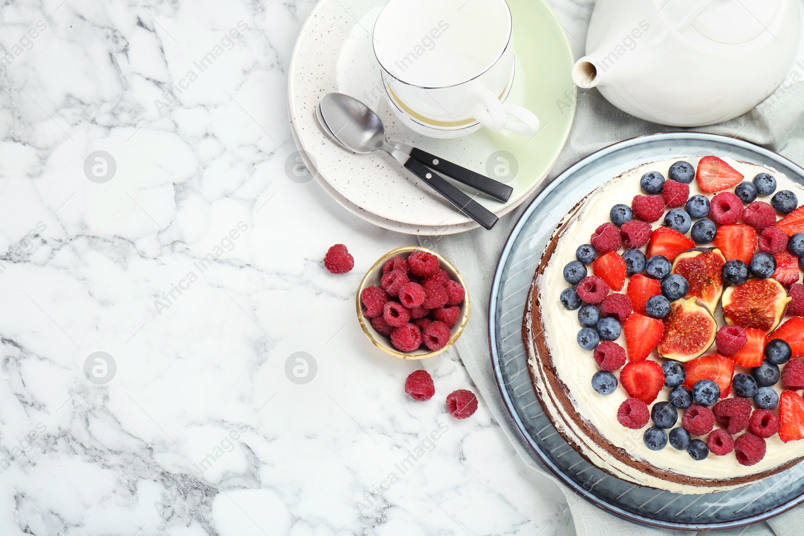 Photo of Delicious chocolate sponge cake with berries served on white marble table, flat lay. Space for text