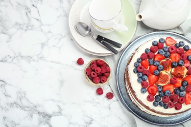 Photo of Delicious chocolate sponge cake with berries served on white marble table, flat lay. Space for text