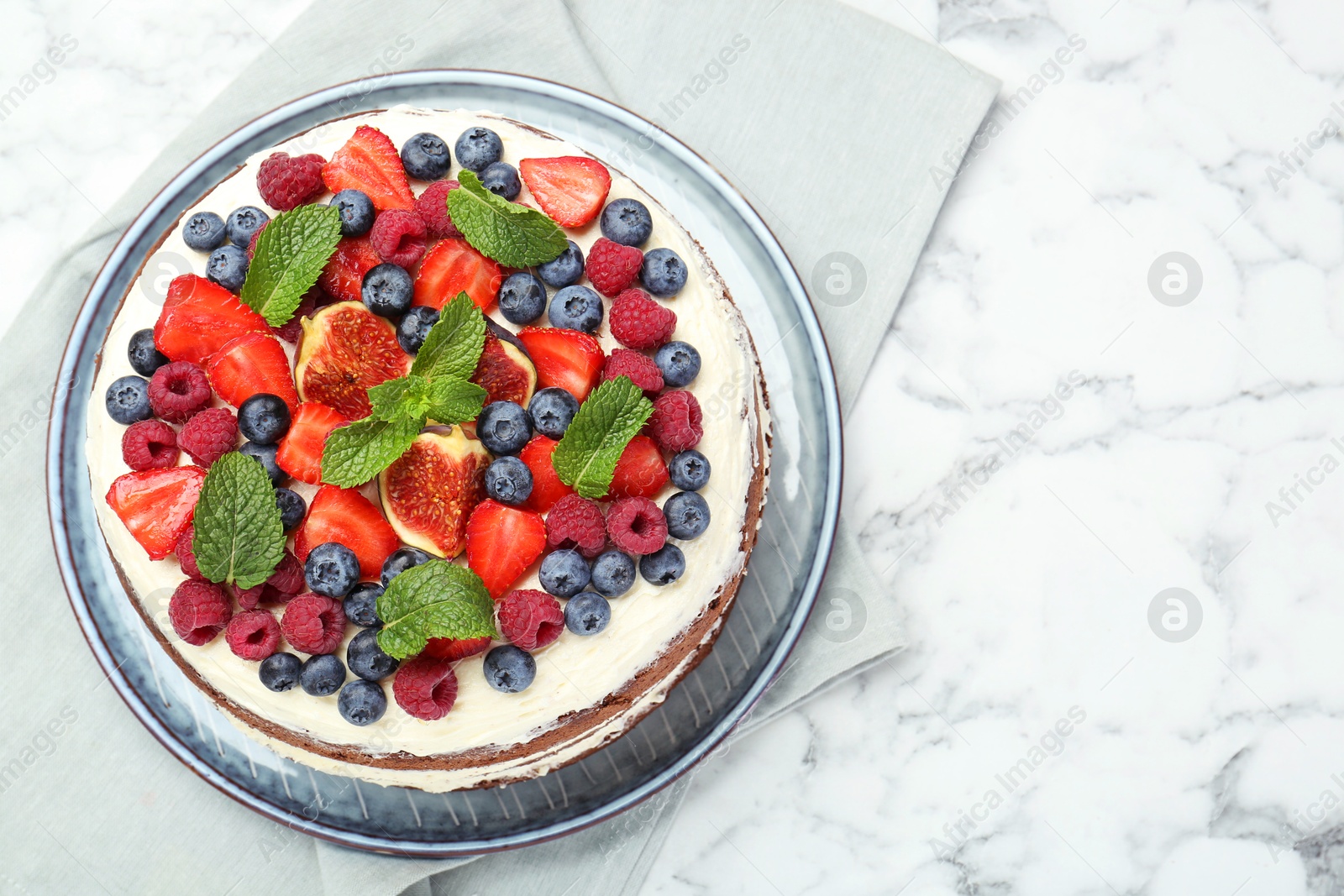 Photo of Delicious chocolate sponge cake with berries on white marble table, top view. Space for text