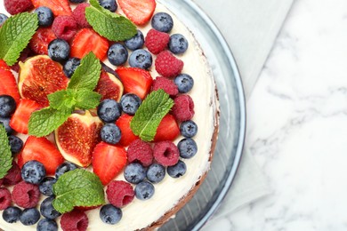 Photo of Delicious chocolate sponge cake with berries on white marble table, top view