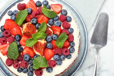 Photo of Delicious chocolate sponge cake with berries and server on white marble table, top view