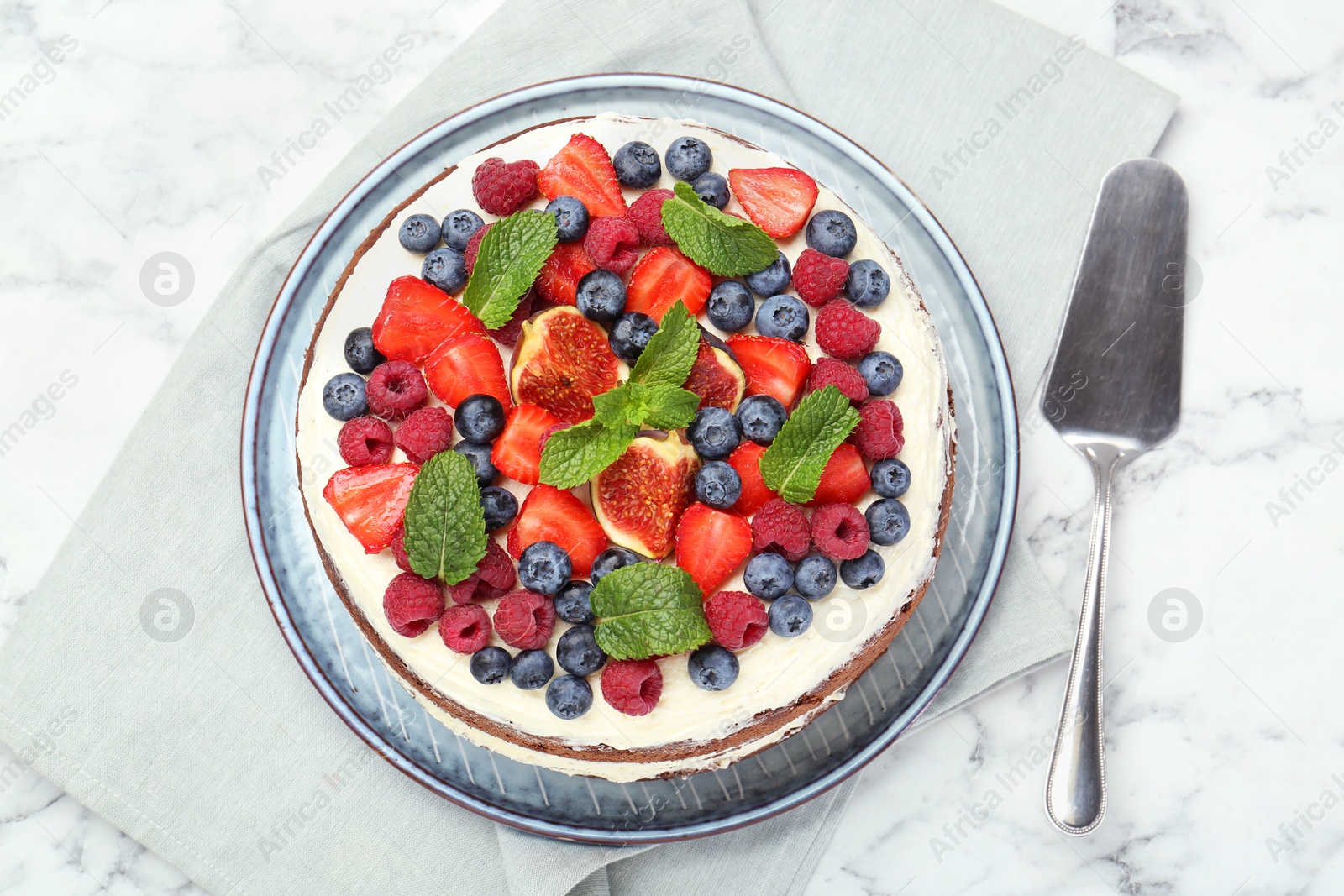 Photo of Delicious chocolate sponge cake with berries and server on white marble table, top view