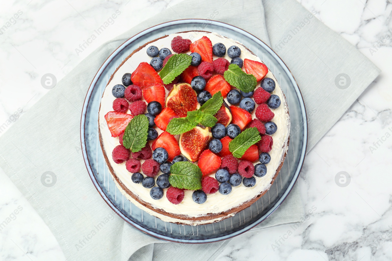 Photo of Delicious chocolate sponge cake with berries on white marble table, top view