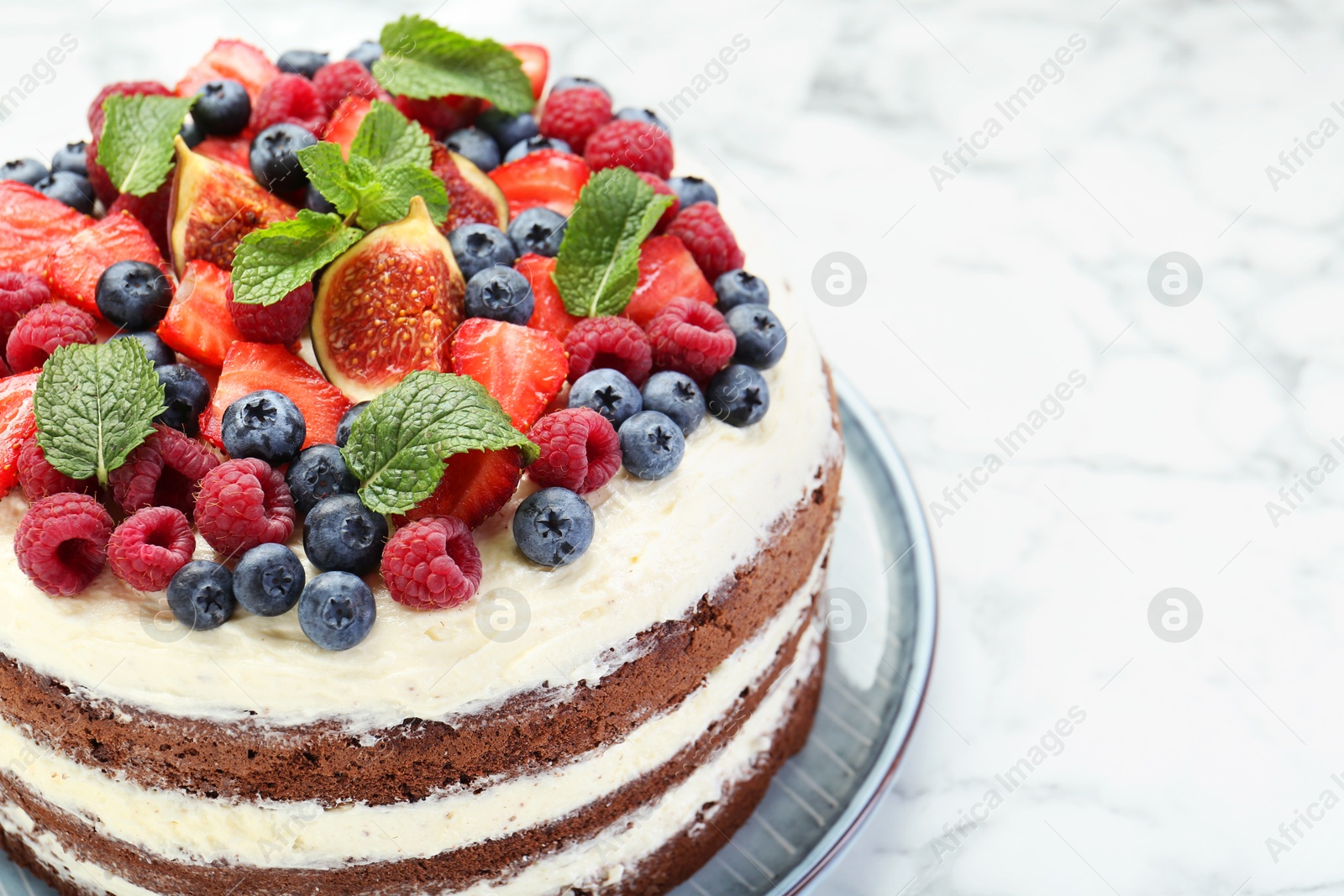 Photo of Delicious chocolate sponge cake with berries on white table, closeup