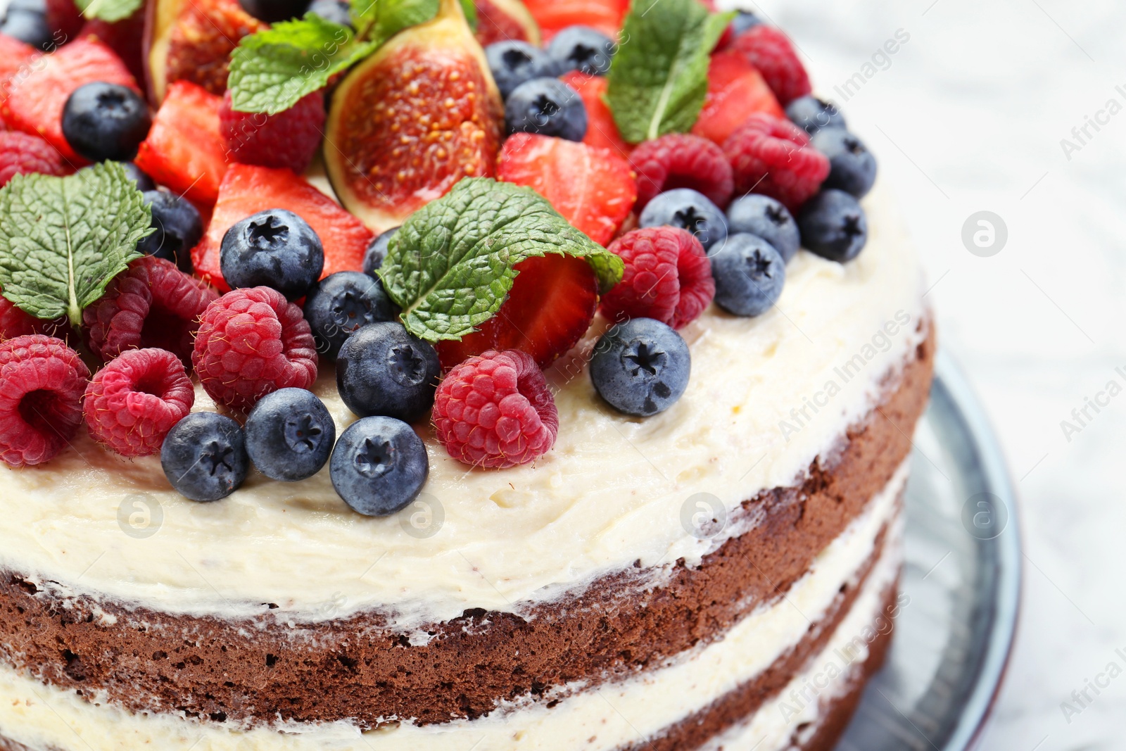 Photo of Delicious chocolate sponge cake with berries on white table, closeup