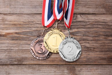 Photo of Golden, silver and bronze medals on wooden background, top view