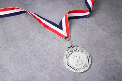 Photo of Silver medal with striped ribbon on grey background