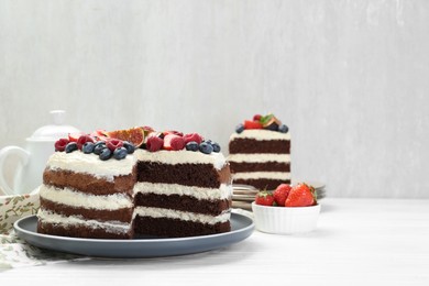 Photo of Delicious chocolate sponge cake with berries served on white wooden table