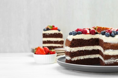 Photo of Delicious chocolate sponge cake with berries served on white wooden table, closeup