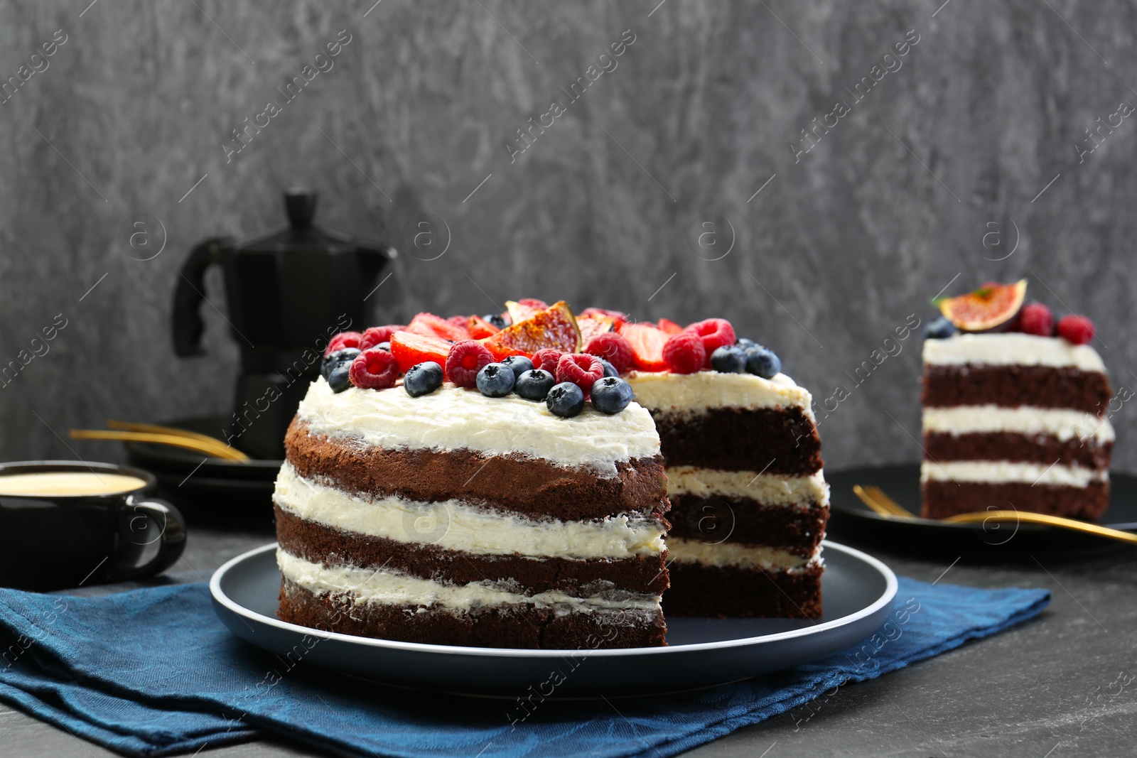 Photo of Delicious chocolate sponge cake with berries served on black table