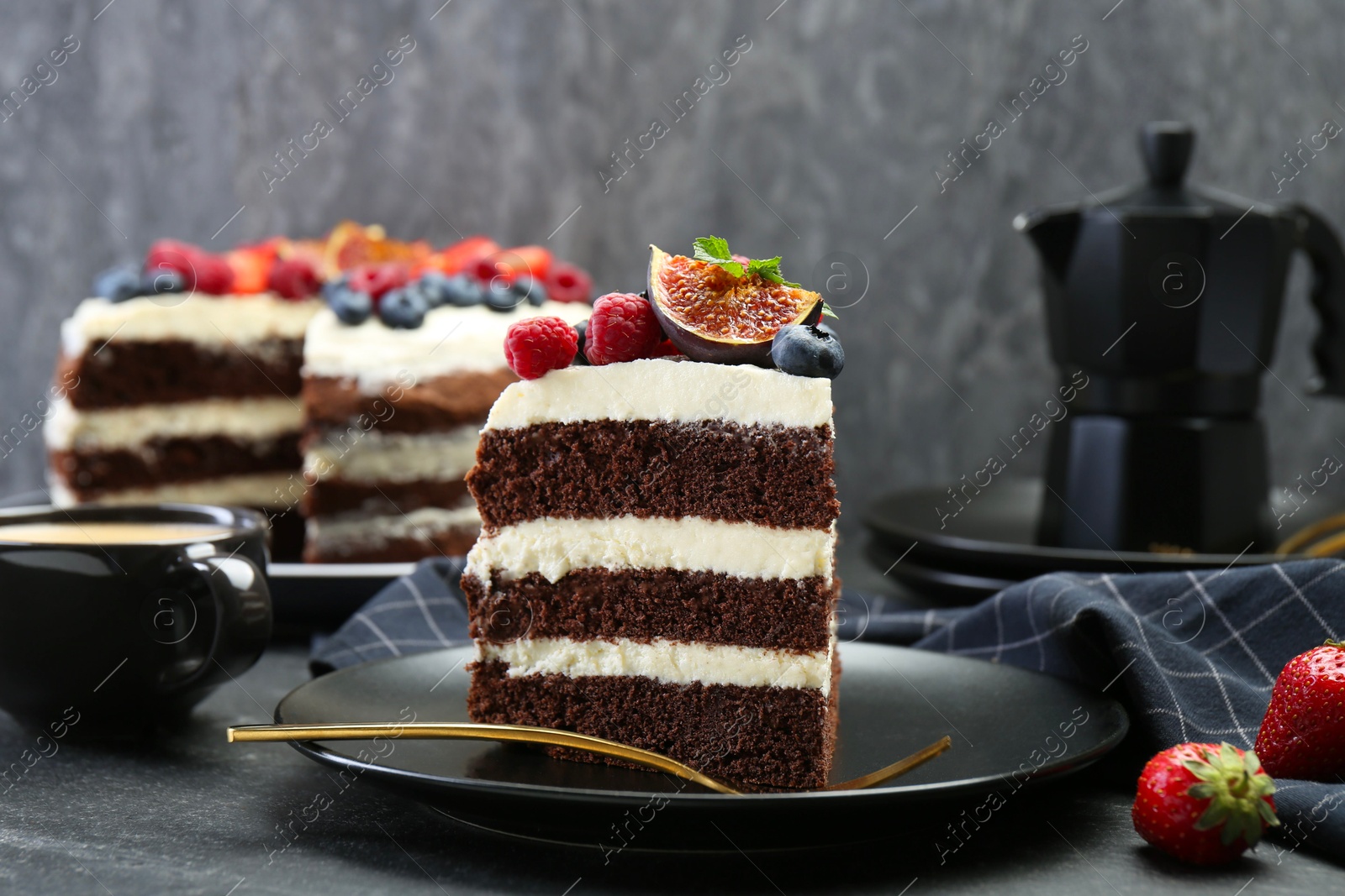 Photo of Piece of delicious chocolate sponge cake with berries and coffee on black table, closeup