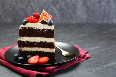 Photo of Piece of delicious chocolate sponge cake with berries on black table, closeup