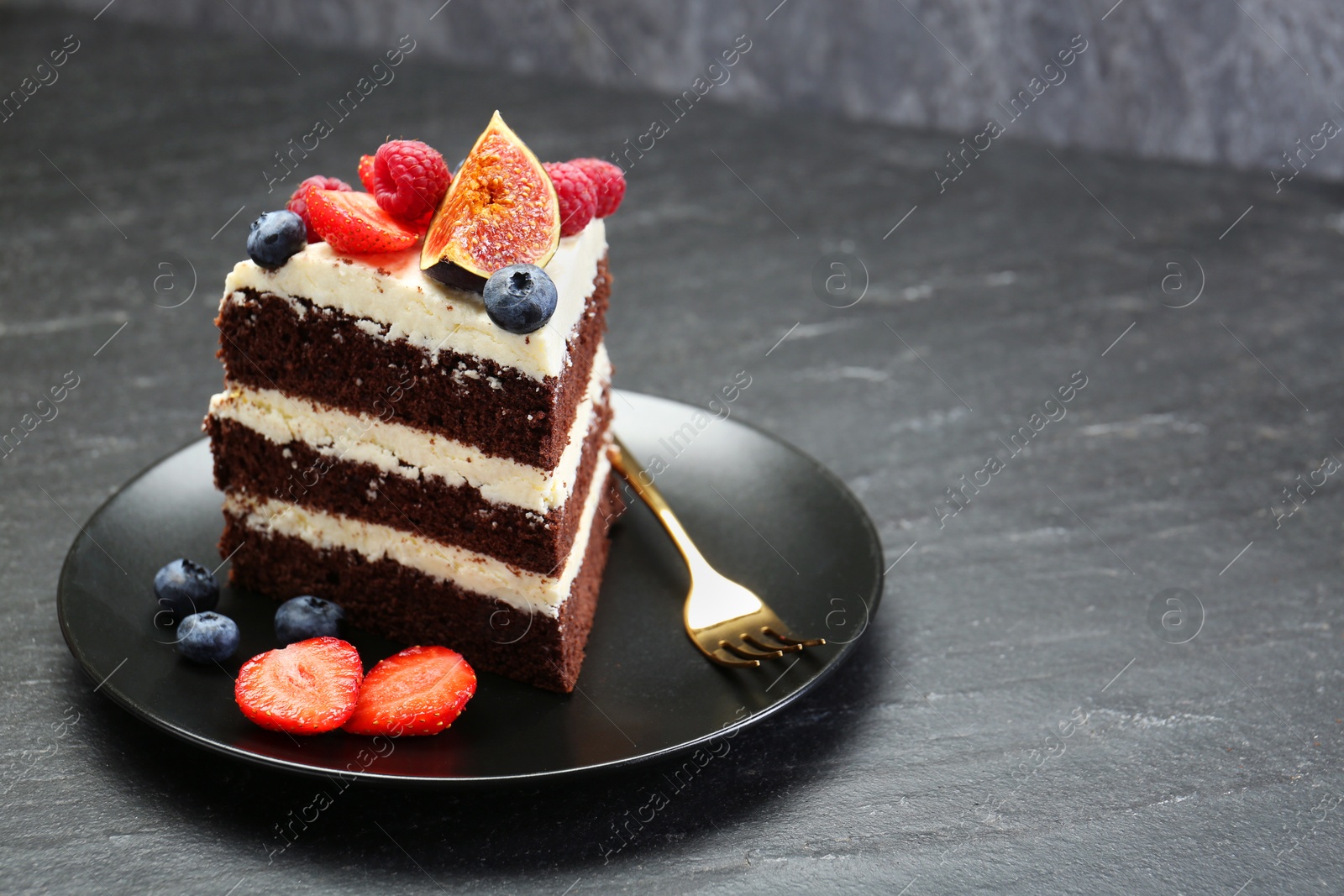 Photo of Piece of delicious chocolate sponge cake with berries on black table, closeup