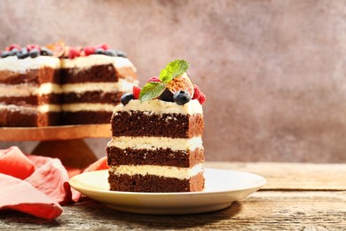 Photo of Piece of delicious chocolate sponge cake with berries on wooden table, closeup