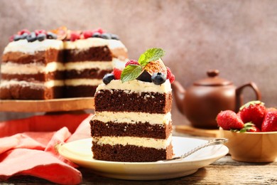 Photo of Piece of delicious chocolate sponge cake with berries on wooden table, closeup