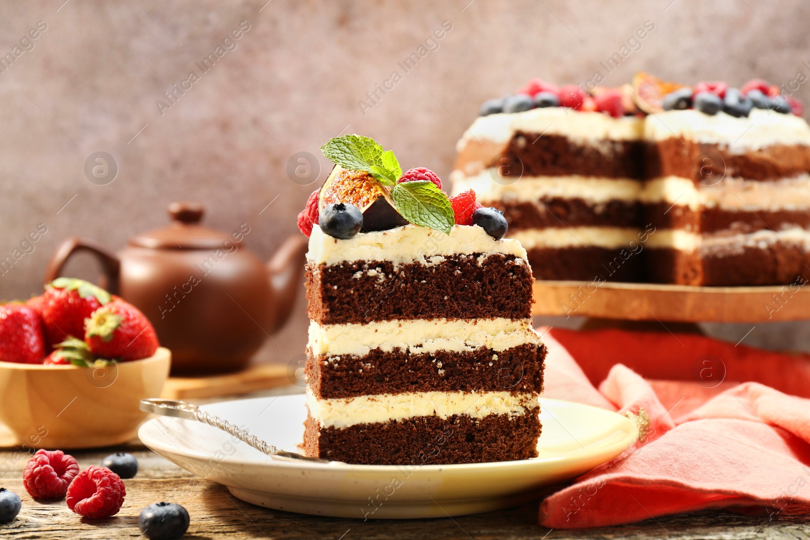 Photo of Piece of delicious chocolate sponge cake with berries on wooden table, closeup