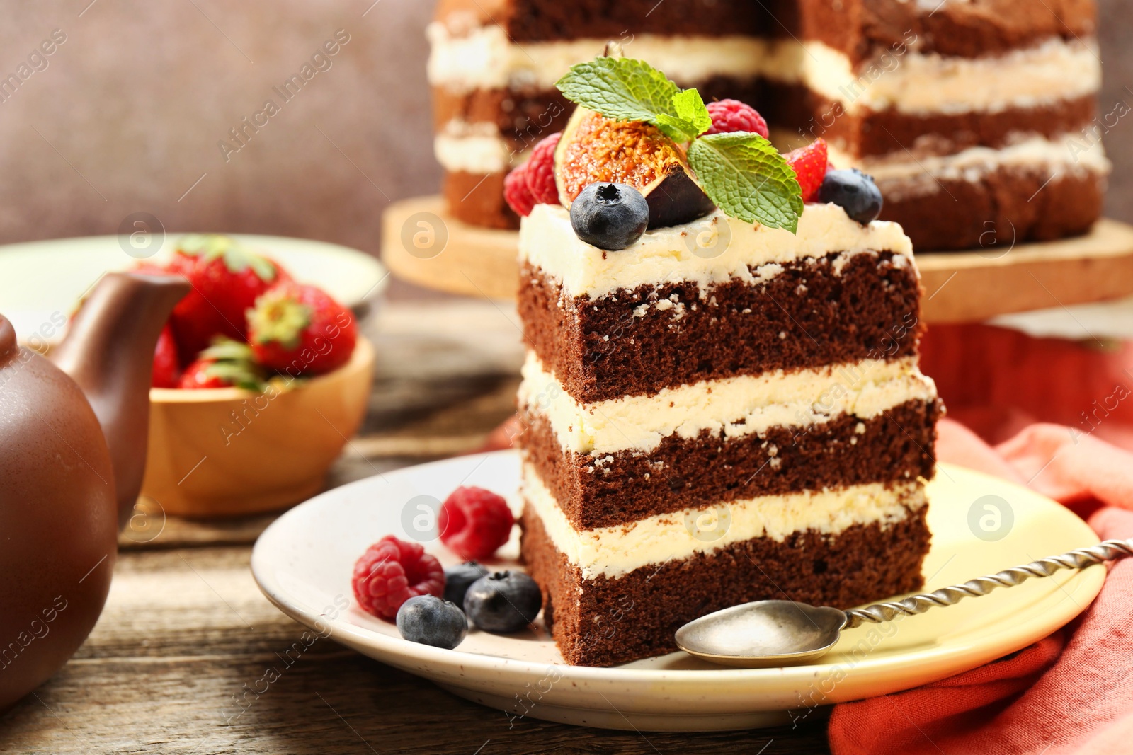 Photo of Piece of delicious chocolate sponge cake with berries served on wooden table, closeup