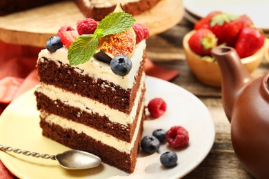 Photo of Piece of delicious chocolate sponge cake with berries served on wooden table, closeup