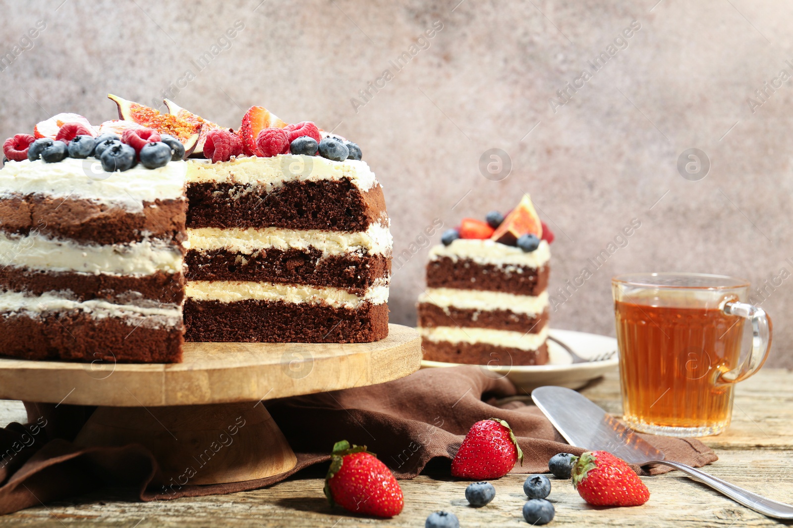 Photo of Delicious chocolate sponge cake with berries served on wooden table