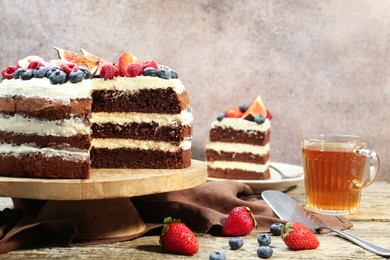 Photo of Delicious chocolate sponge cake with berries served on wooden table