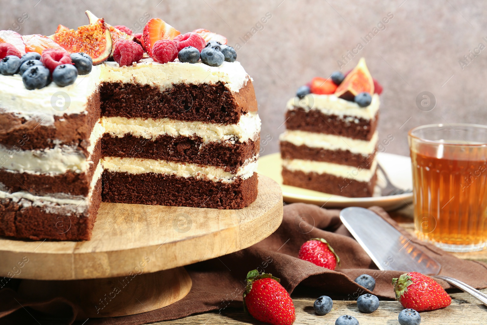 Photo of Delicious chocolate sponge cake with berries served on wooden table